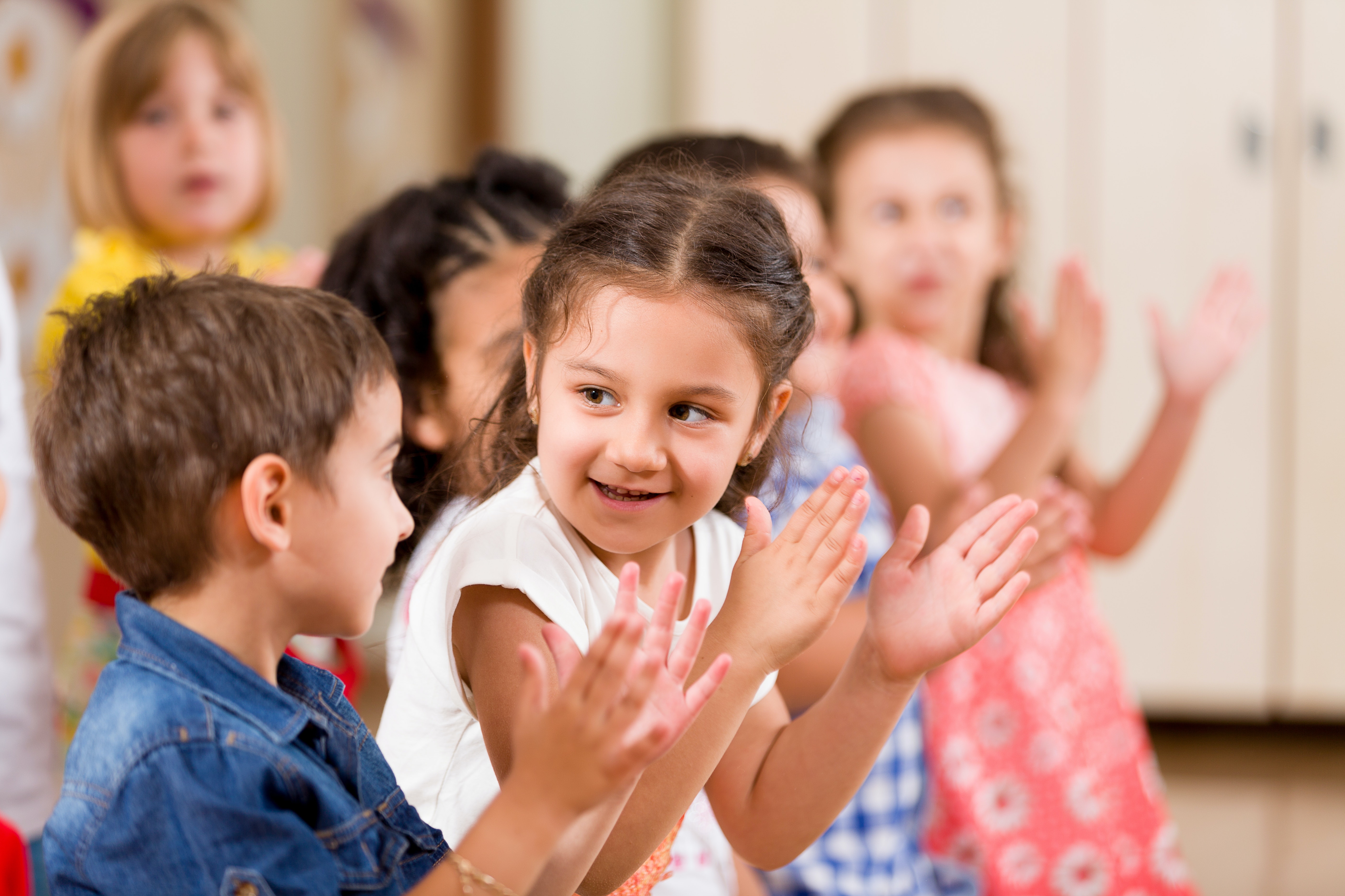 Kids likely in a childcare centre clapping hands